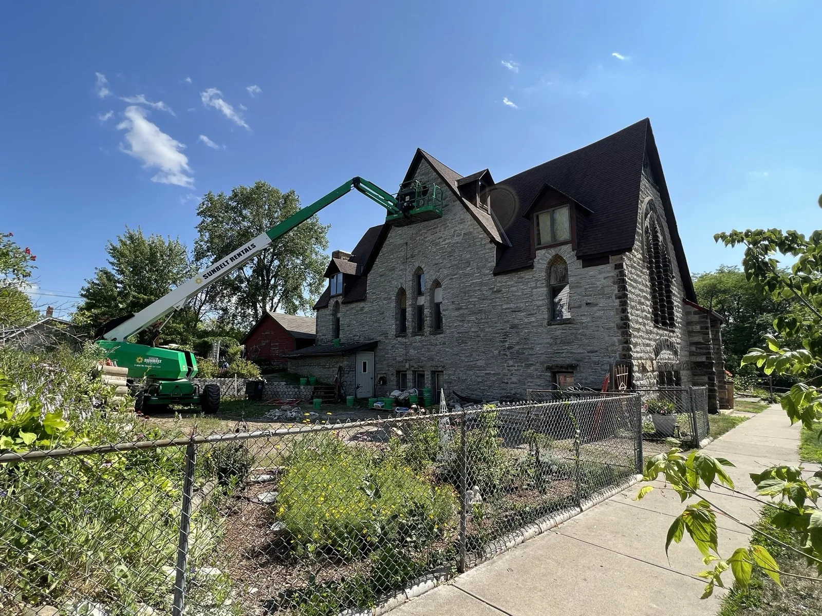 Stone church under masonry restoration with a boom lift at the dormers